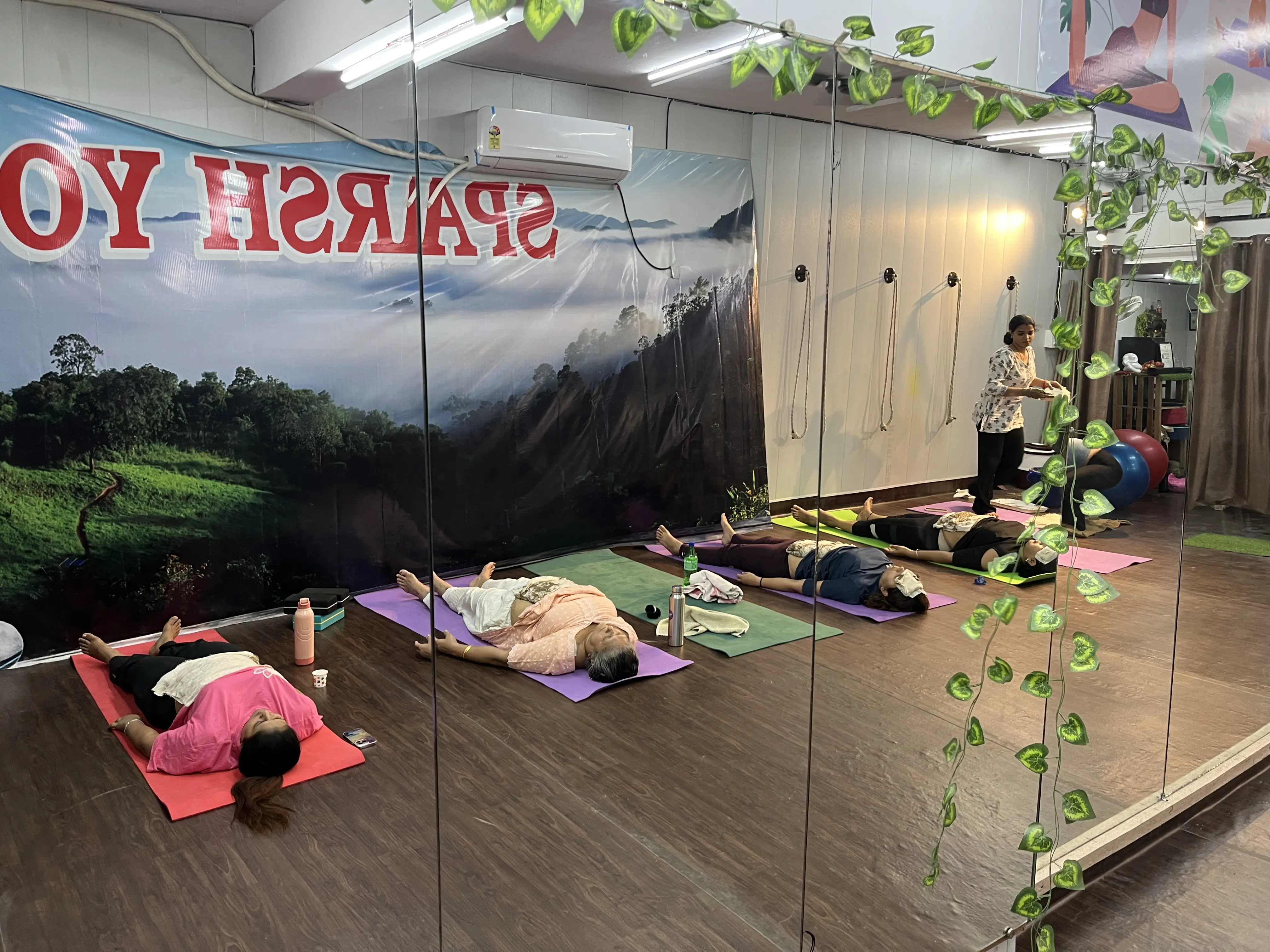 Group mud therapy Mitti Chikitsa session at Sparsh Yog studio Delhi NCR — students resting with mud packs under Jyoti Singh's guidance